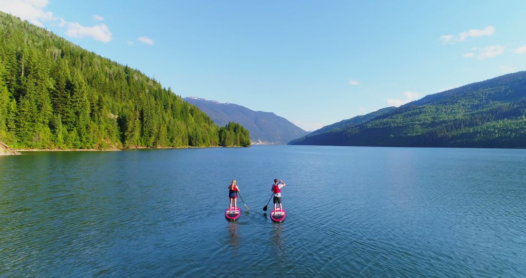Paddleboarding adventure on serene lake amidst lush forests