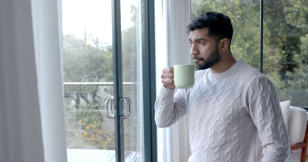 Young Man Drinking Coffee by Window in Cozy Home - Free Images, Stock Photos and Pictures on Pikwizard.com