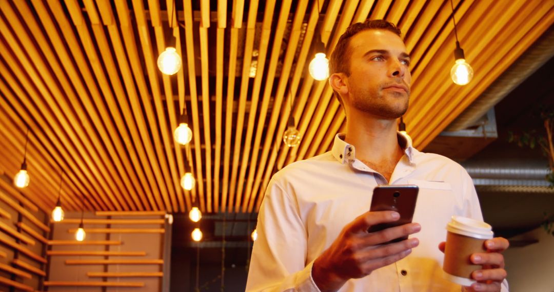 Confident Young Executive Using Phone in Modern Cafe