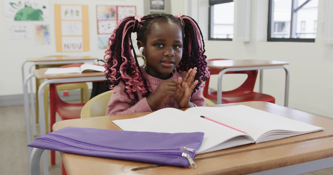 Child Sitting at School Desk Clapping Hands in Classroom