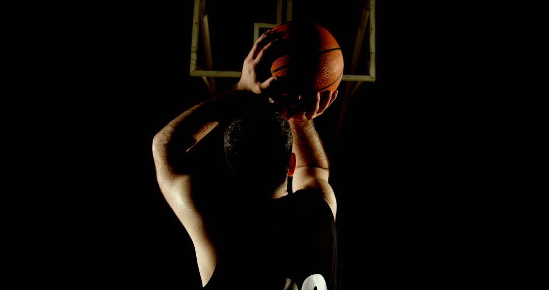 Silhouetted Basketball Player Shooting in Dark Gym