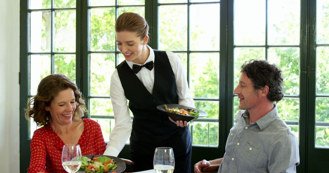 Smiling Waitress Serving Couple in Bright Restaurant
