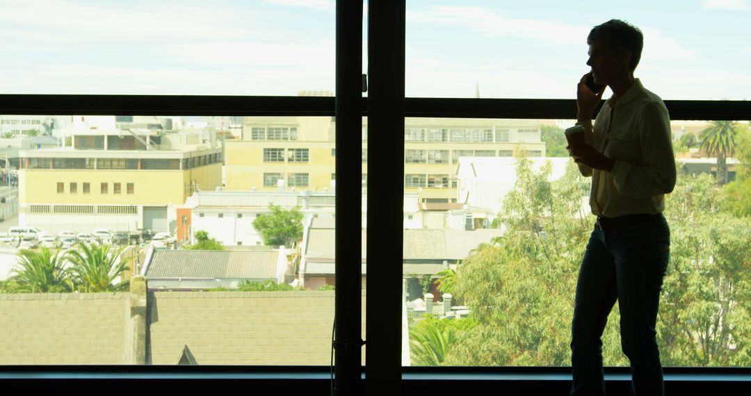 Businessman talking on phone by office window - Free Images, Stock Photos and Pictures on Pikwizard.com