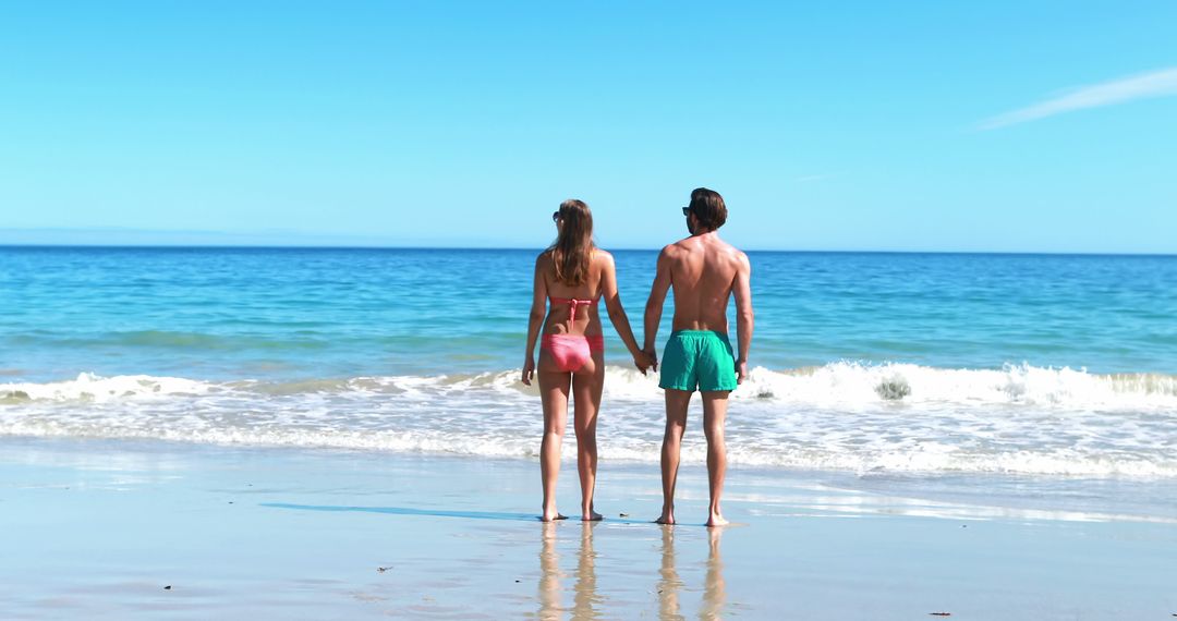 Rear view of couple holding hands while walking on beach 4k - Free Images, Stock Photos and Pictures on Pikwizard.com