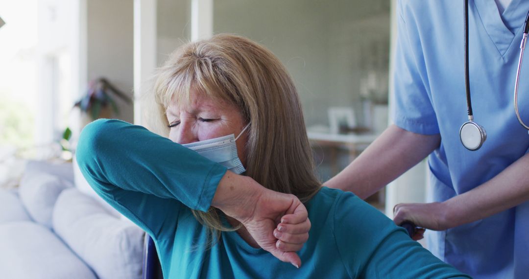 Senior Woman Coughing into Elbow while Wearing Mask Assisted by Nurse - Free Images, Stock Photos and Pictures on Pikwizard.com