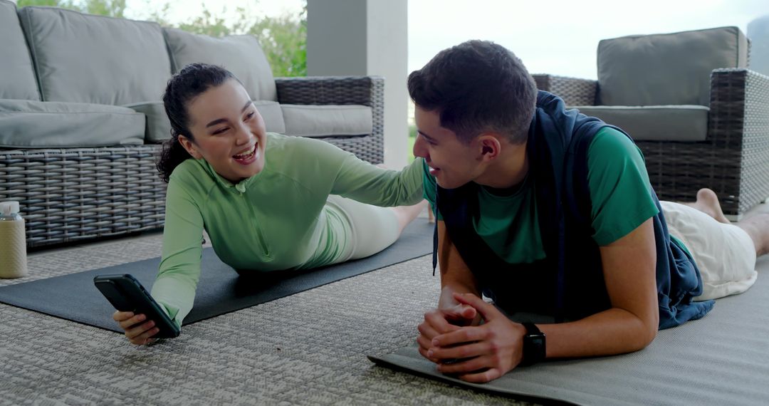 Couple Enjoys Outdoor Workout Break with Gadgets on Patio