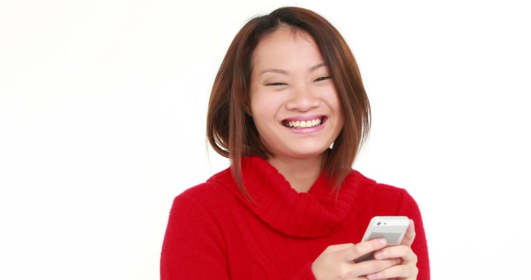 Smiling Asian Woman in Red Sweater Using Smartphone - Free Images, Stock Photos and Pictures on Pikwizard.com