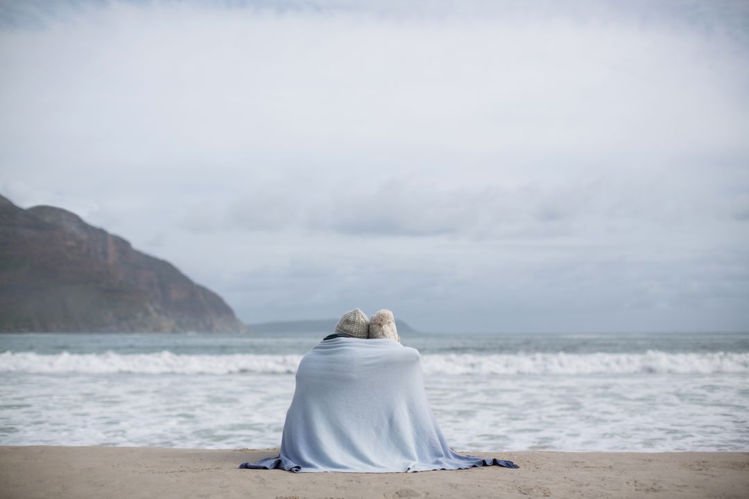 Mature Couple Wrapped in Blanket on Beach - Free Images, Stock Photos and Pictures on Pikwizard.com