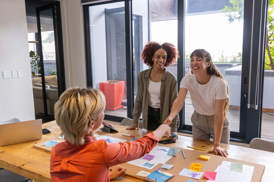 Diverse Female Coworkers Shaking Hands Over Office Collaboration