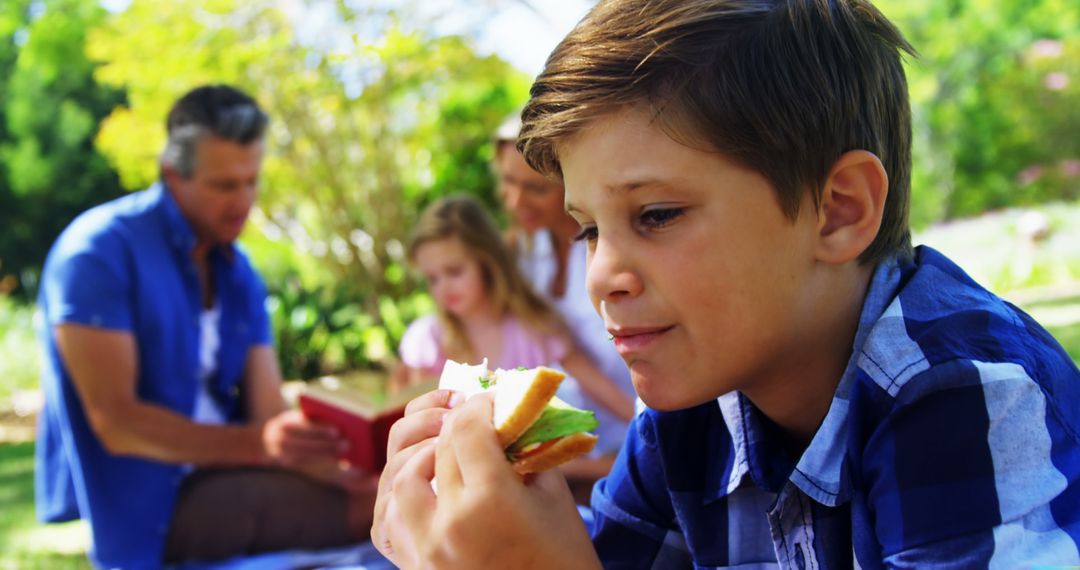 Boy Eating Sandwich During Family Picnic in Park - Free Images, Stock Photos and Pictures on Pikwizard.com