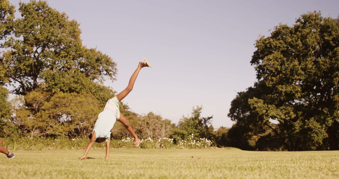 Young Girl Doing Cartwheel on Grassy Field in Summer - Free Images, Stock Photos and Pictures on Pikwizard.com