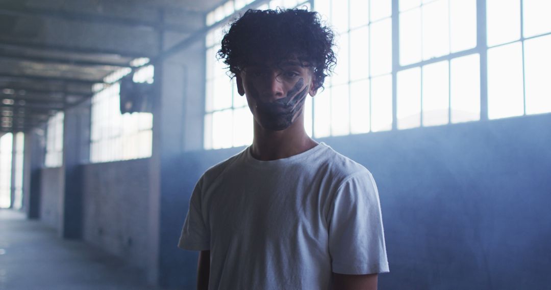 Young Man with Painted Face in Industrial Space Expressing Identity
