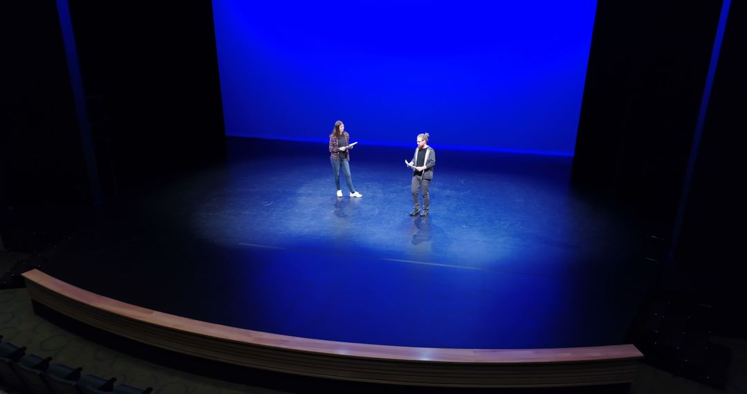 Two actors engage in a scene on stage against a blue backdrop, embodying theatrical artistry. - Free Images, Stock Photos and Pictures on Pikwizard.com