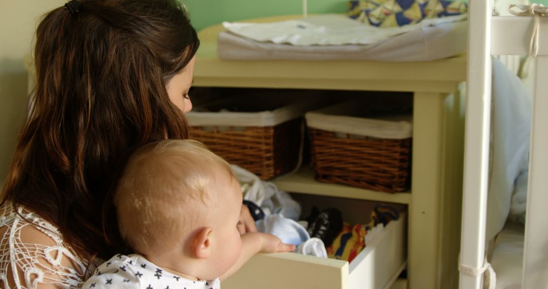 Mother Holding Baby Organizing Nursery Drawer - Free Images, Stock Photos and Pictures on Pikwizard.com