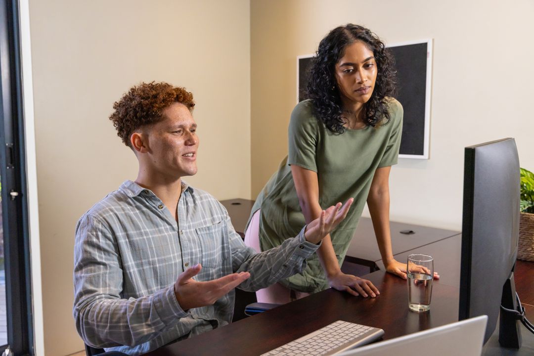 Diverse Colleagues Collaborating Over Computer in Modern Office Environment