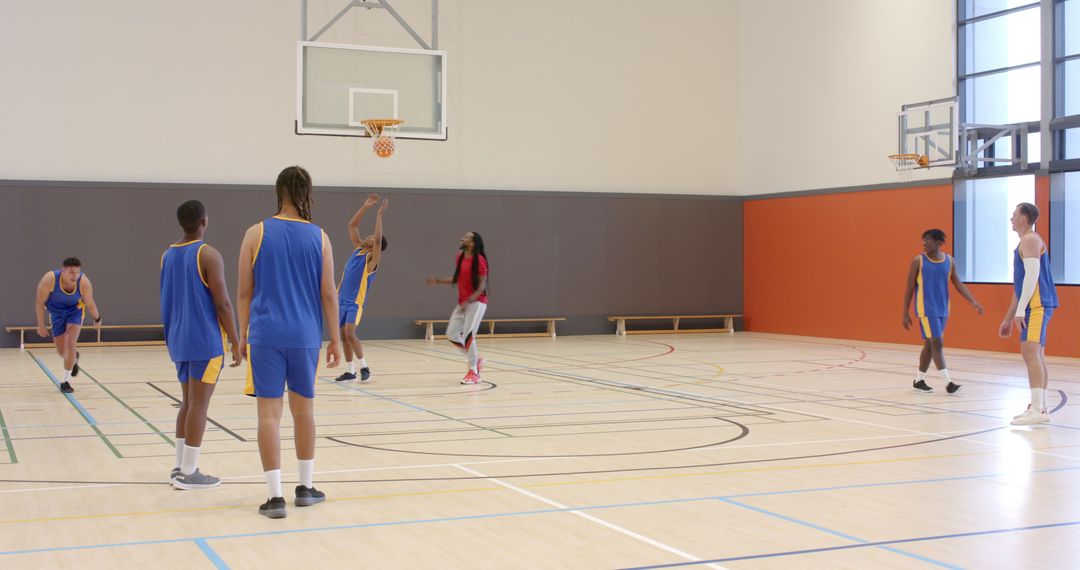 Diverse Team Practicing Basketball with Coach on Indoor Court