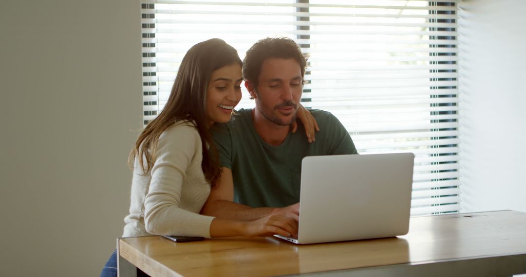 Couple Collaborating Over Laptop in Sunlit Home Workspace