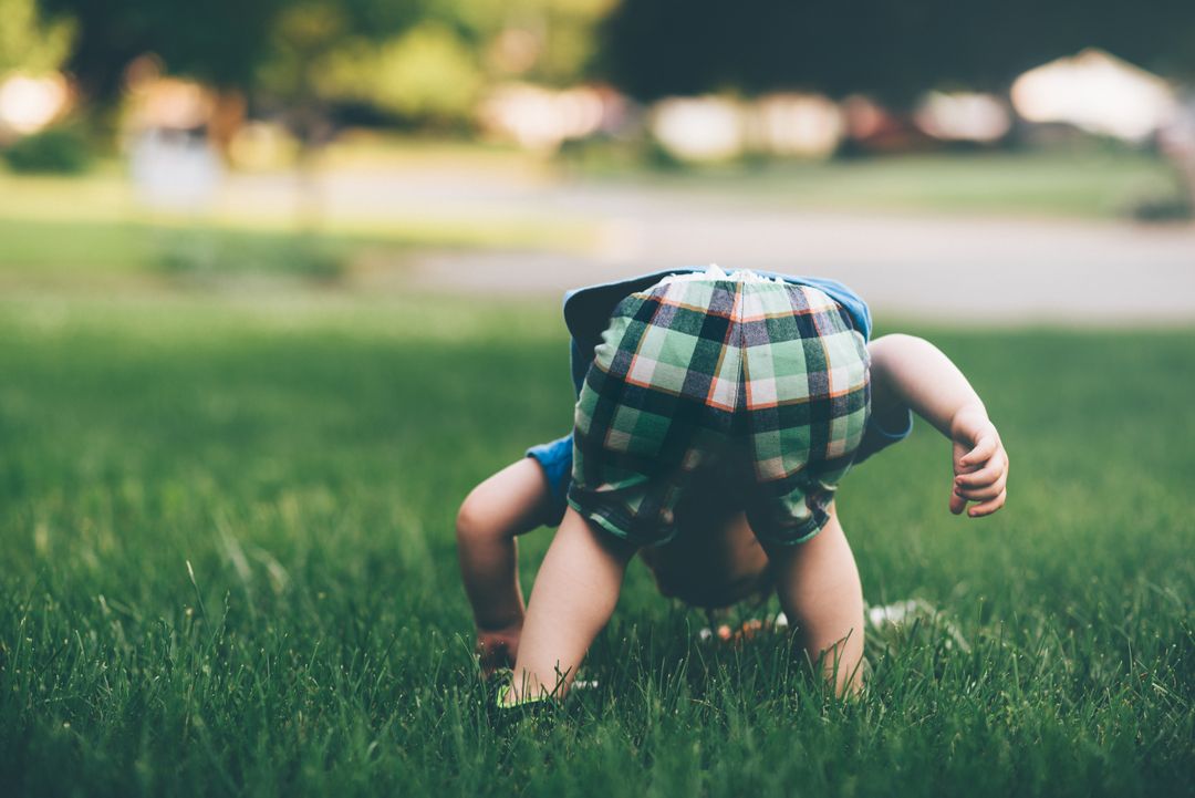 Baby in Colorful Shorts Bending Over on Green Grass Lawn - Free Images, Stock Photos and Pictures on Pikwizard.com