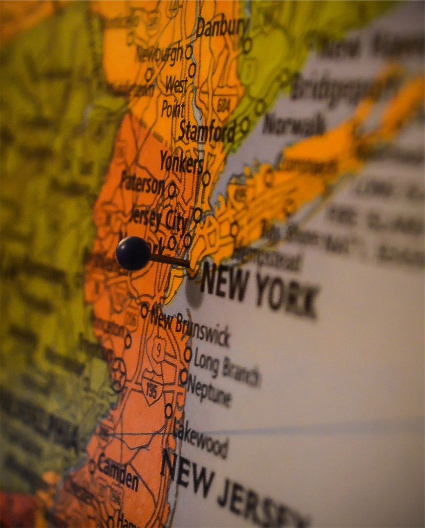 Pushpin marking New York metropolitan area on vintage map close-up with shallow depth