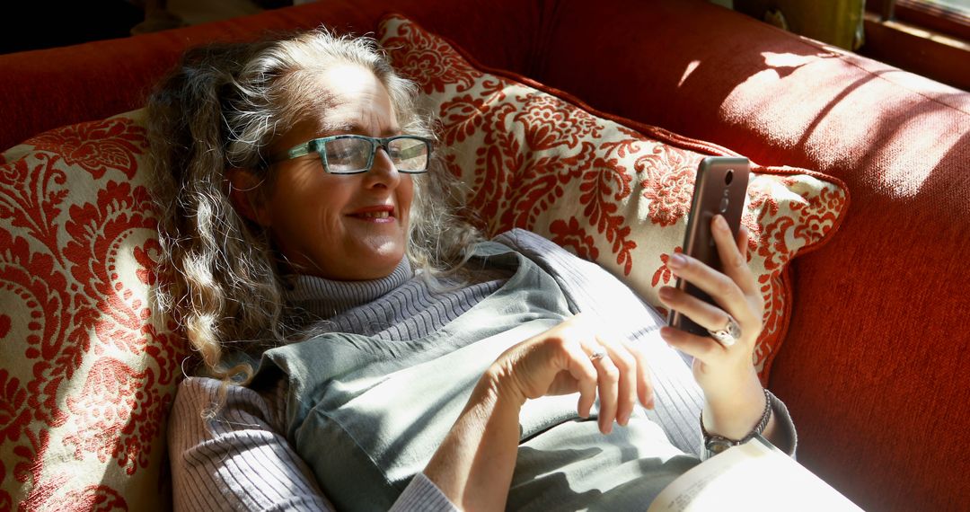 Older Woman Relaxing at Home, Smiling at Smartphone - Free Images, Stock Photos and Pictures on Pikwizard.com