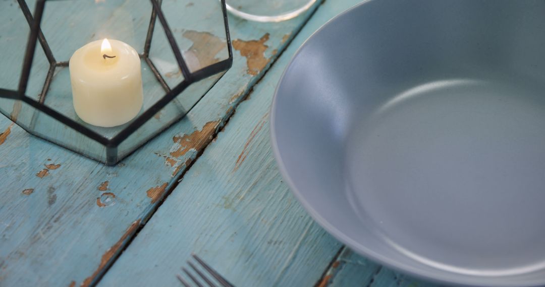 A rustic table setting features a blue plate and a lit candle in a lantern, with copy space - Free Images, Stock Photos and Pictures on Pikwizard.com