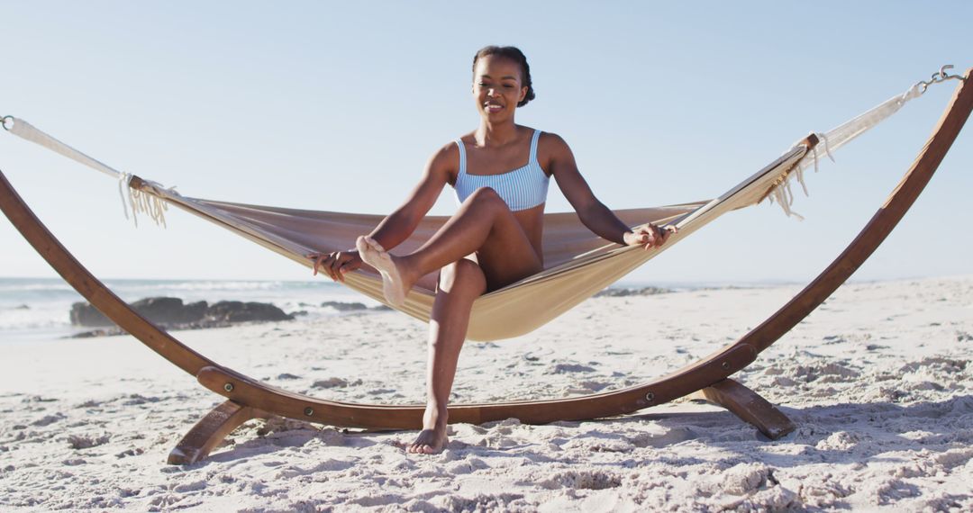 African american woman sitting on a hammock at the beach - Free Images, Stock Photos and Pictures on Pikwizard.com
