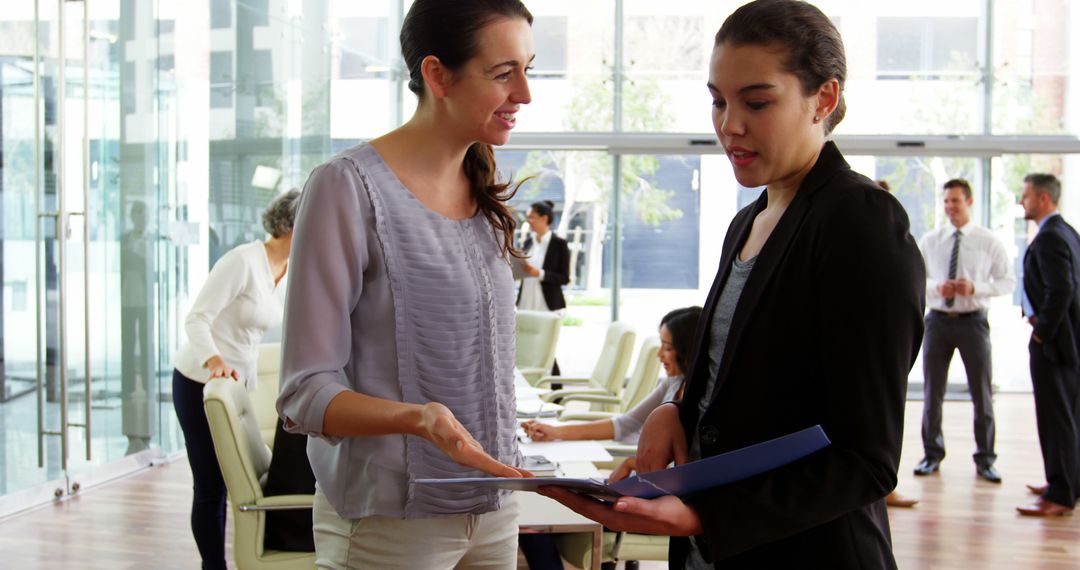 Professional Businesswomen Discussing Documents in Modern Office