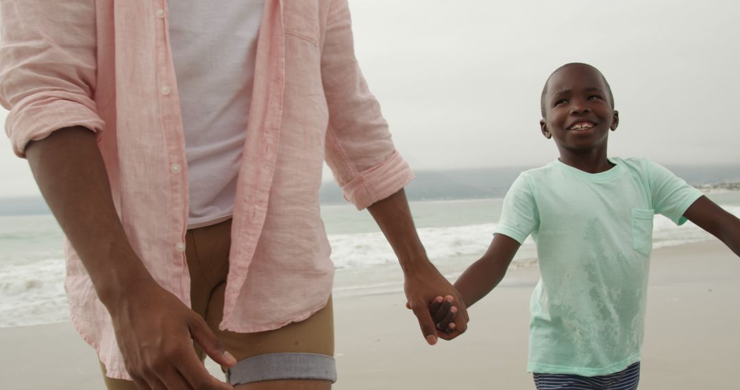 African american father and son holding hands on beach - Free Images, Stock Photos and Pictures on Pikwizard.com