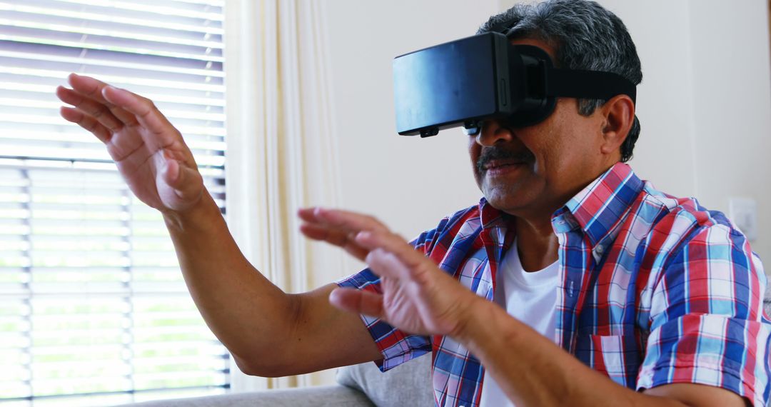 Senior Man Using Virtual Reality Headset at Home Reaching Out - Free Images, Stock Photos and Pictures on Pikwizard.com