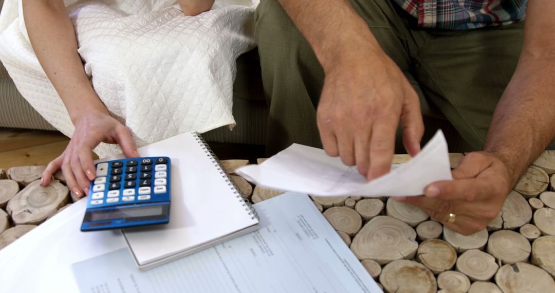 Couple Budgeting Finances with Calculator at Home