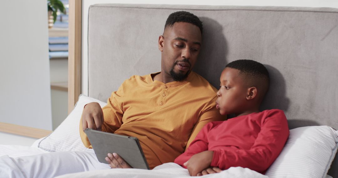 Father and Son Bonding Over Digital Tablet in Cozy Bedroom