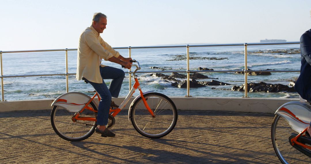 Senior Man Riding Bike Along Seaside Boardwalk at Sunset - Free Images, Stock Photos and Pictures on Pikwizard.com