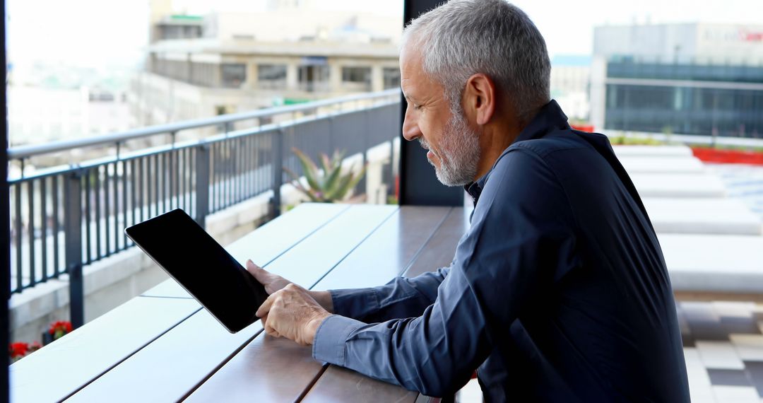 Senior Man Using Tablet on Outdoor Terrace - Free Images, Stock Photos and Pictures on Pikwizard.com