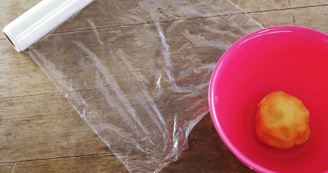 Food Preparation with Pink Bowl and Plastic Wrap on Wooden Surface - Free Images, Stock Photos and Pictures on Pikwizard.com