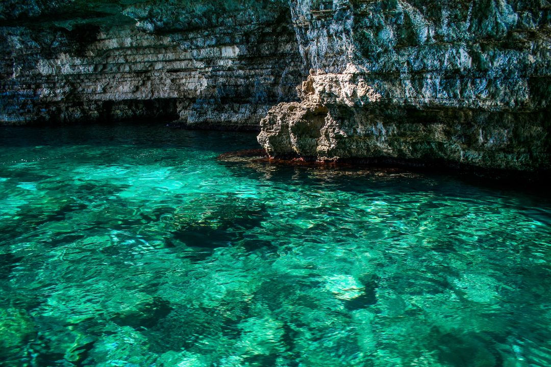 Serene Coastal Cave with Crystal Clear Water and Rocky Cliff - Free Images, Stock Photos and Pictures on Pikwizard.com