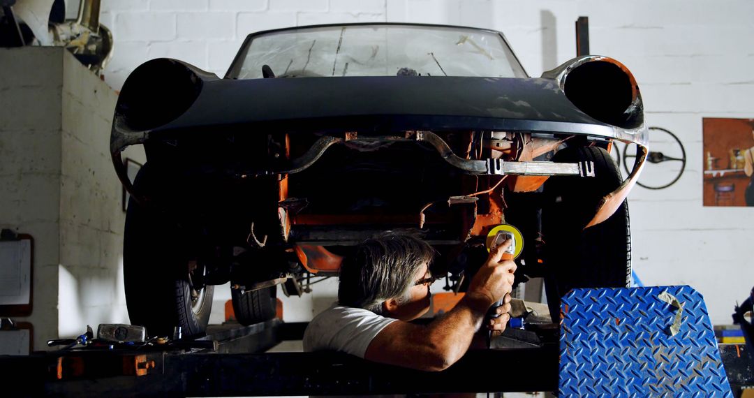 Caucasian man works on a car in a garage - Free Images, Stock Photos and Pictures on Pikwizard.com