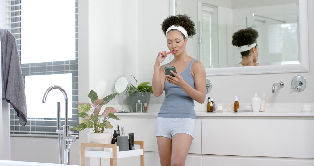 Woman Brushing Teeth and Using Smartphone in Modern Bathroom - Free Images, Stock Photos and Pictures on Pikwizard.com