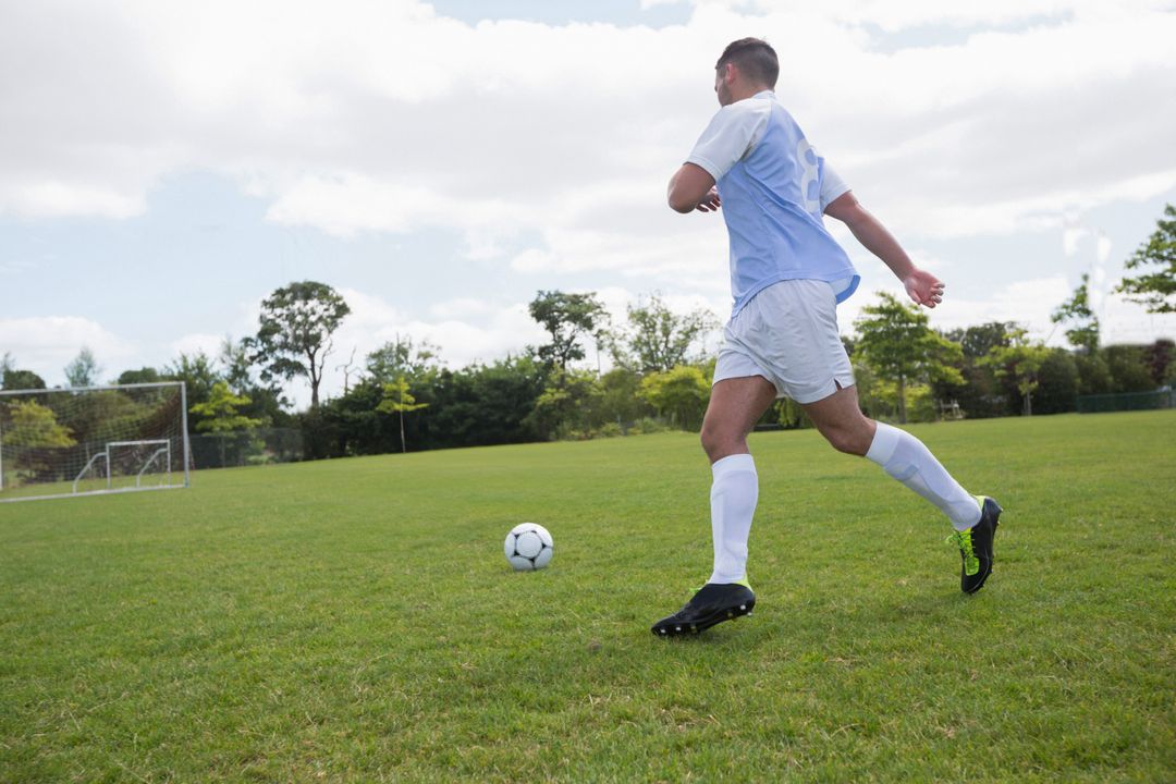 Soccer Player Running Towards Ball on Field in Action-Packed Game