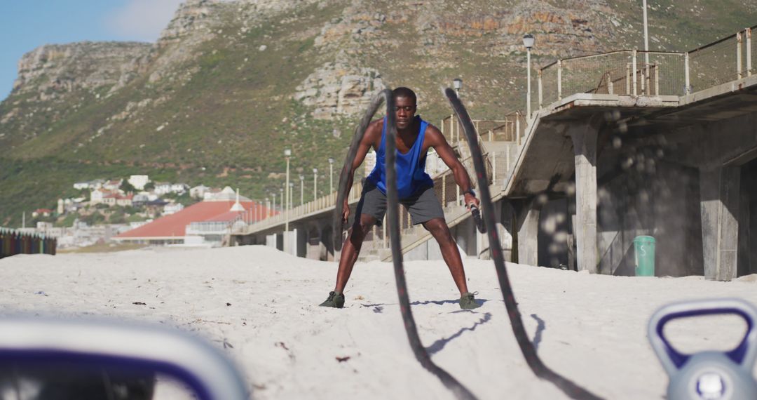 Man Exercising with Battle Ropes on Sandy Beach with Mountains in Background - Free Images, Stock Photos and Pictures on Pikwizard.com