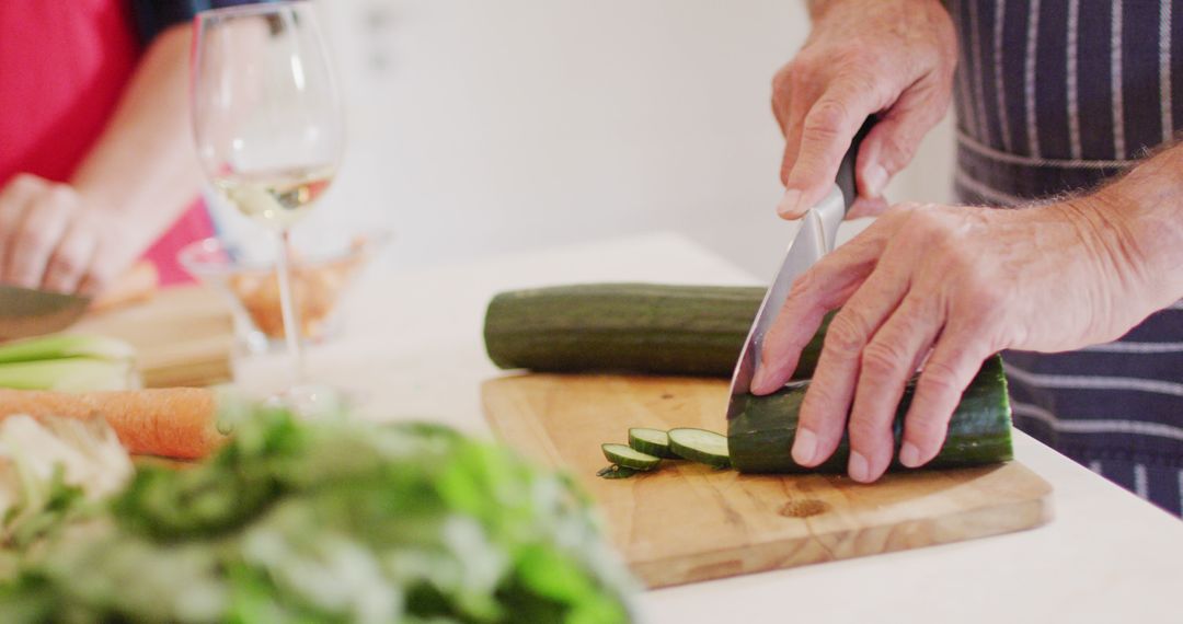 Senior Man Slicing Cucumber on Wooden Board in Modern Kitchen - Free Images, Stock Photos and Pictures on Pikwizard.com