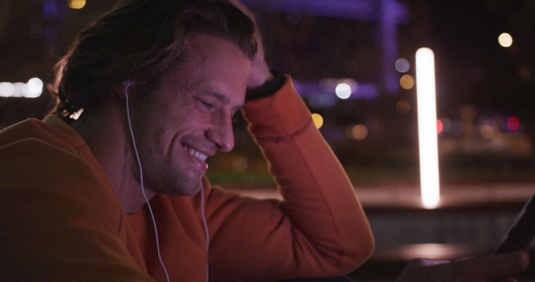 Man Smiling During Video Call at Night in Urban Landscape - Free Images, Stock Photos and Pictures on Pikwizard.com