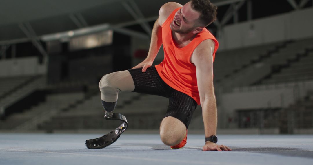 Injured Paralympic Athlete Kneeling on Track with Prosthetic Leg - Free Images, Stock Photos and Pictures on Pikwizard.com