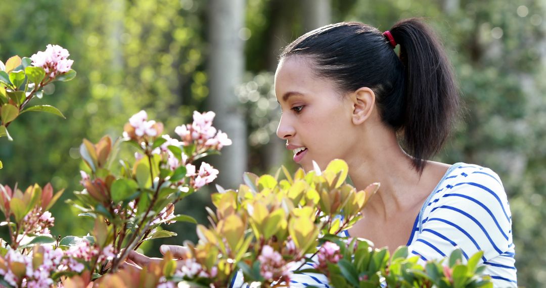 A young African American woman enjoys the beauty of blooming flowers in a garden, with copy space - Free Images, Stock Photos and Pictures on Pikwizard.com