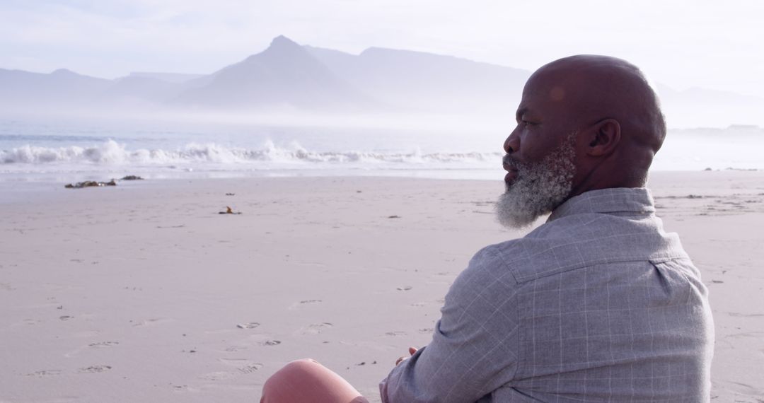 Mature Man Sitting on Beach Contemplating the Horizon - Free Images, Stock Photos and Pictures on Pikwizard.com