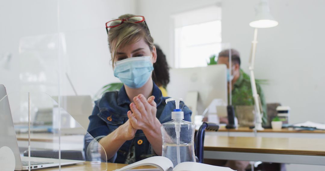 Woman Wearing Face Mask Using Hand Sanitizer in Office - Free Images, Stock Photos and Pictures on Pikwizard.com