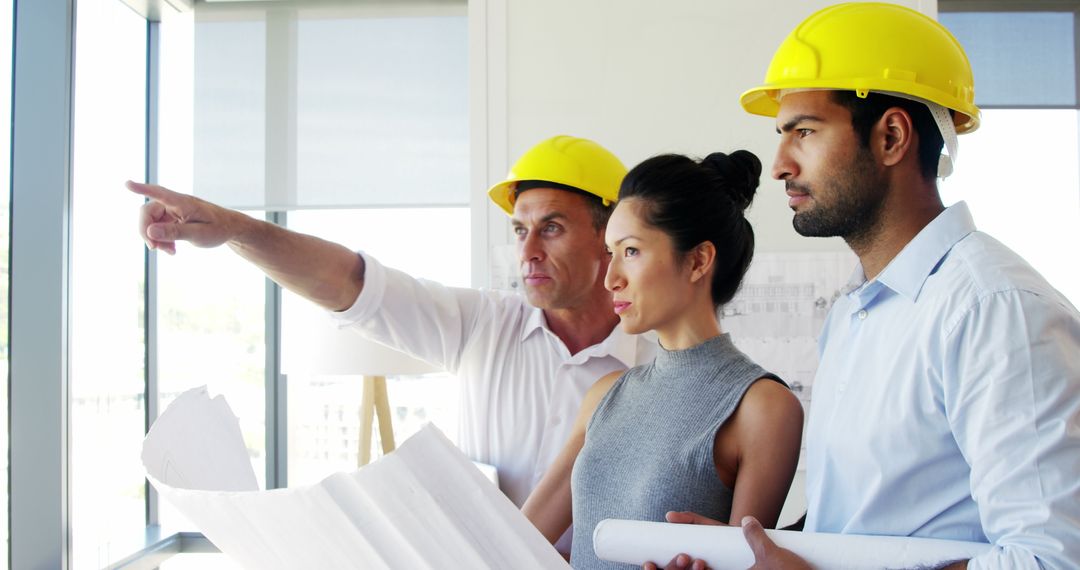 Multi-Ethnic Team of Architects Analyzing Blueprints in Modern Office