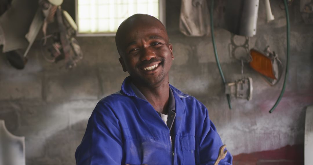 Cheerful African Panel Beater in Workshop Smiling Confidently with Wrench