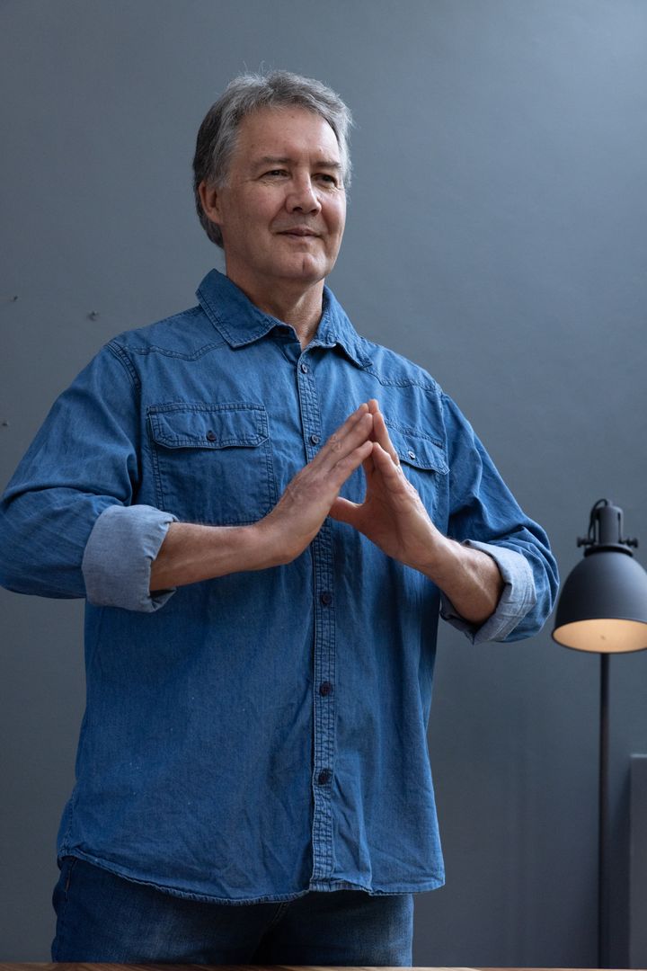 Confident Senior Man in Denim Practicing Steeple Gesture