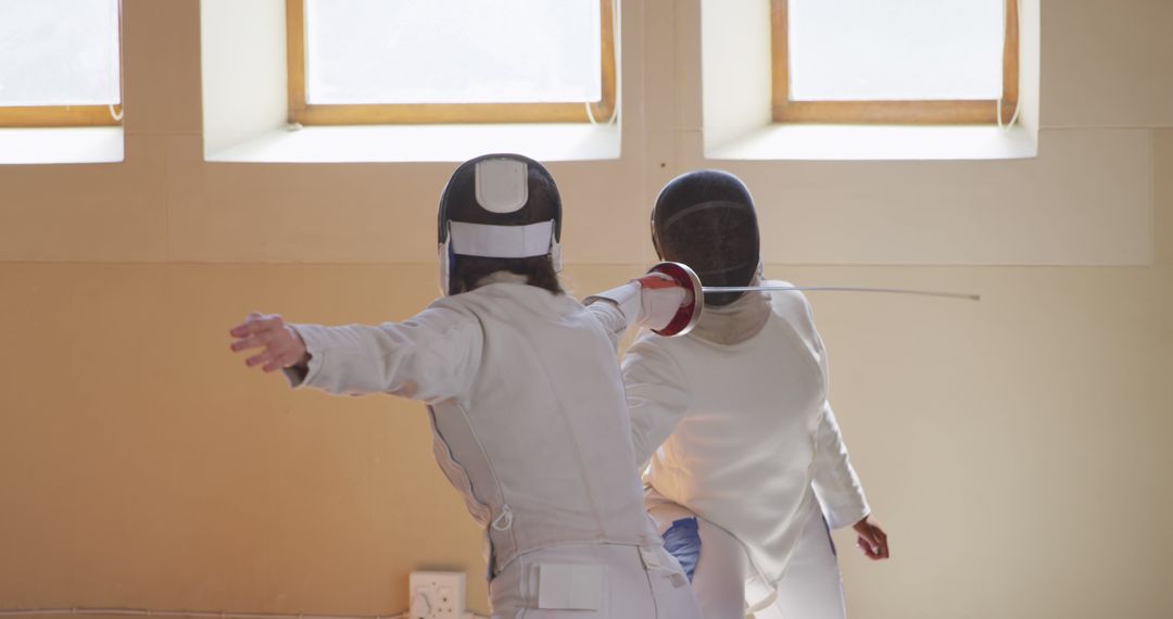 Two Women Engaging in Fencing Duel Indoors with Foil Swords - Free Images, Stock Photos and Pictures on Pikwizard.com