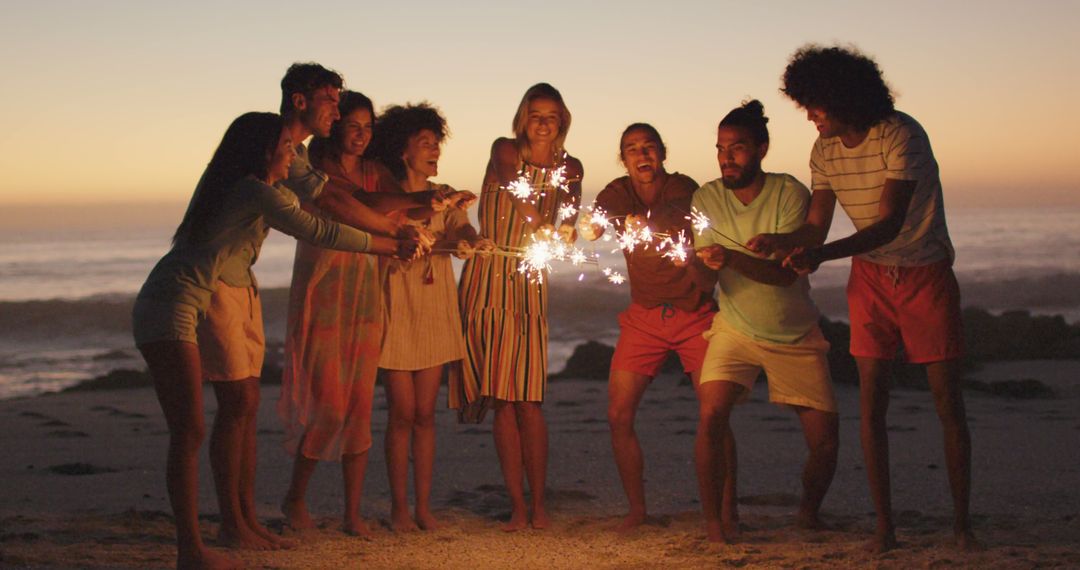 Friends celebrating with sparklers on beach at sunset - Free Images, Stock Photos and Pictures on Pikwizard.com